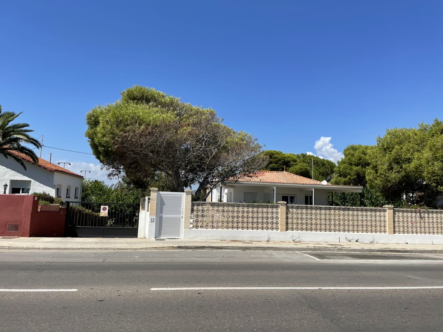 La casa desde la calle, con el muro de celosía y los pinos.