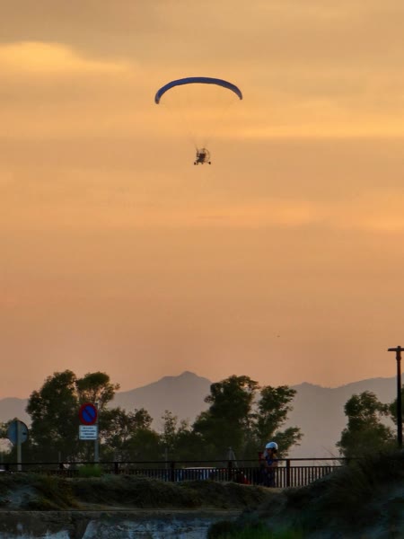 Paramotor sobrevolando la costa al atardecer