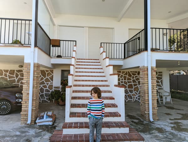 Niño al pie de la escalera de casa