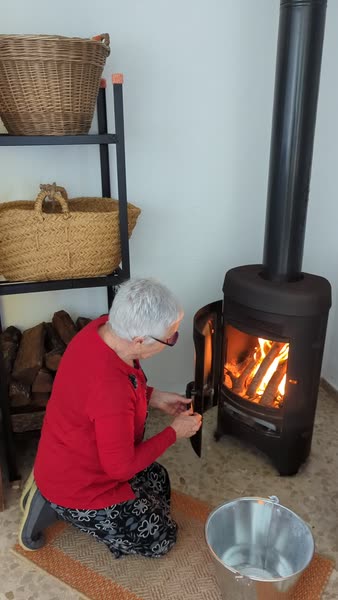 La abuela enciende la estufa de leña