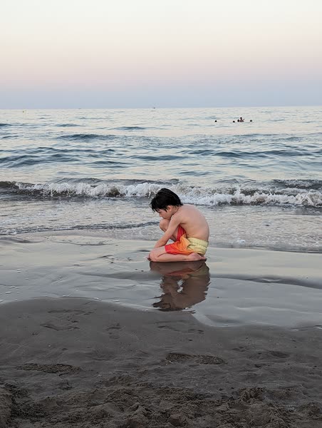 Niño sentado en la orilla al atardecer