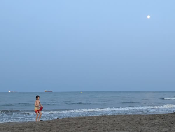 Niño en el mar bajo la luna